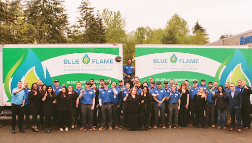 A group photo of the Blue Flame team in front of two service trucks, with employees wearing blue shirts and posing in a large outdoor setting.