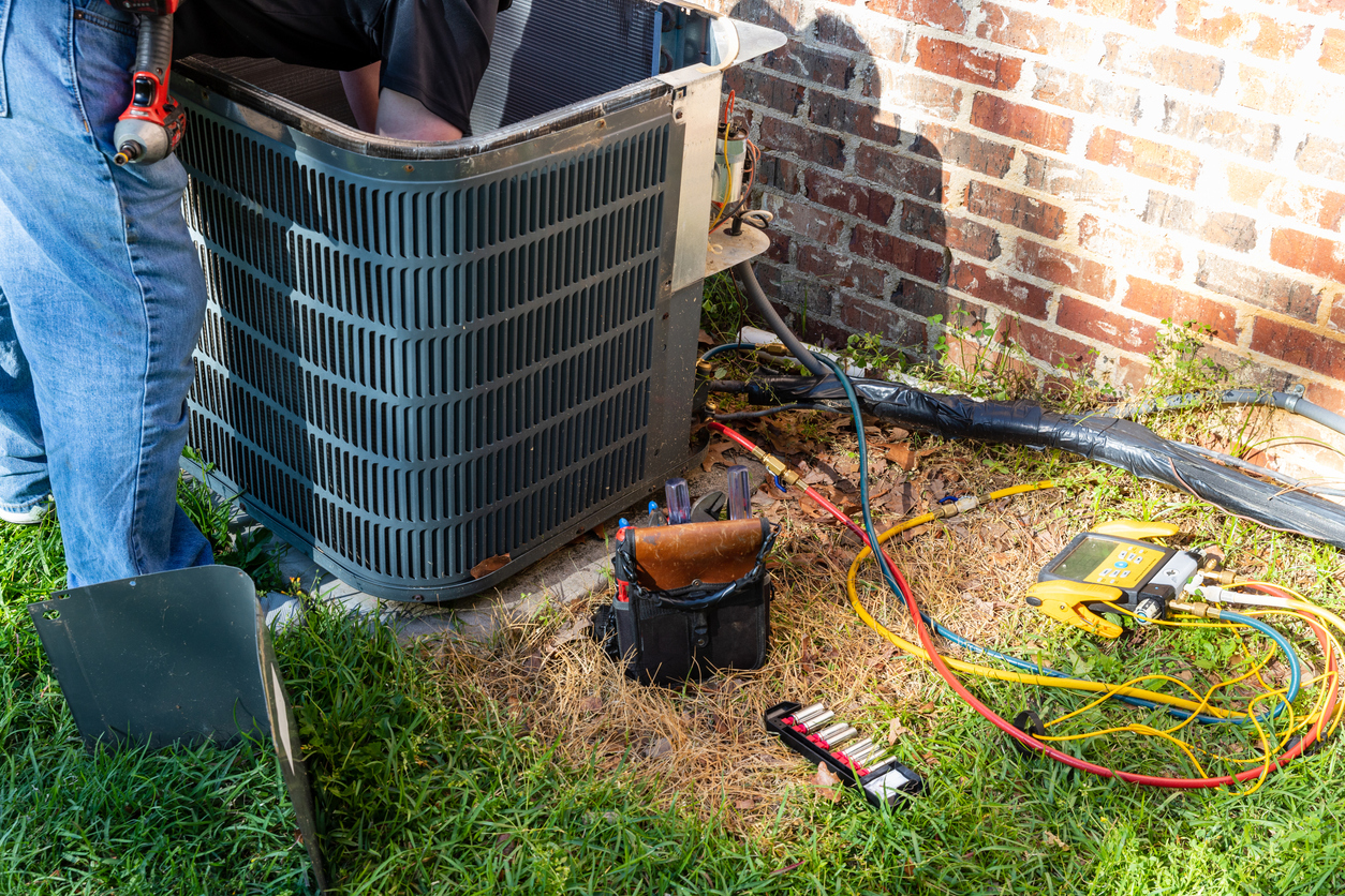 A technician works on an outdoor air conditioning unit during an emergency AC repair in Seattle.